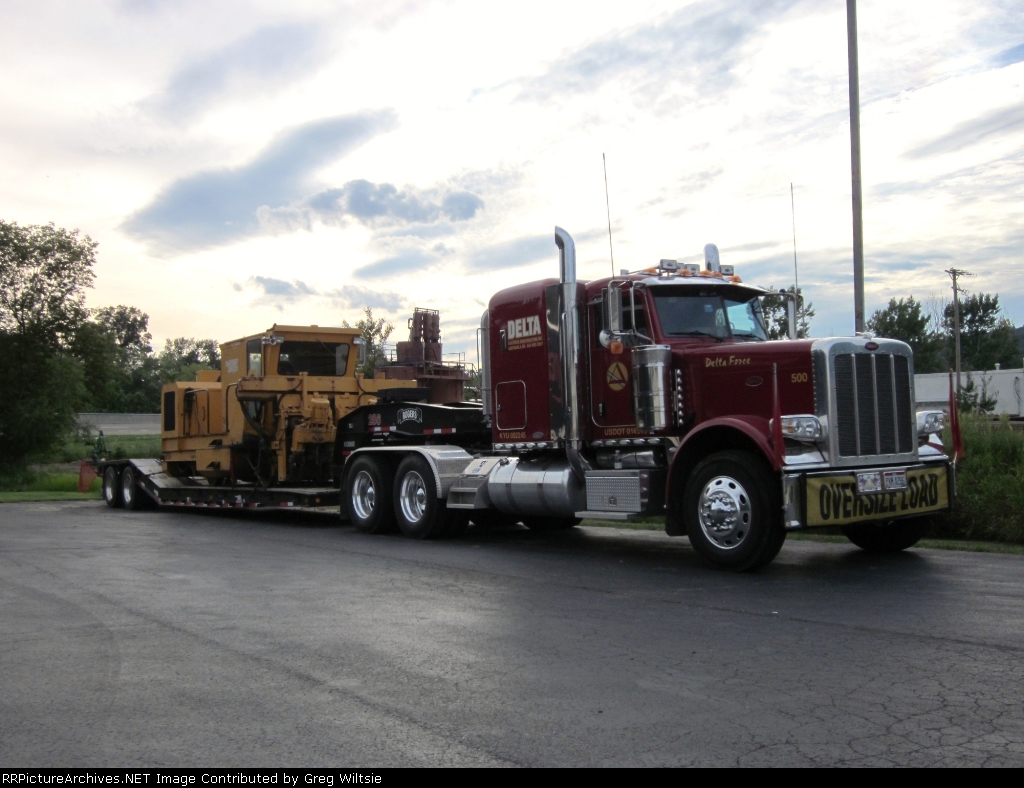 A piece of work equipment from Delta Railroad Construction sits on a flatbed in the Super 8 Motel parking lot